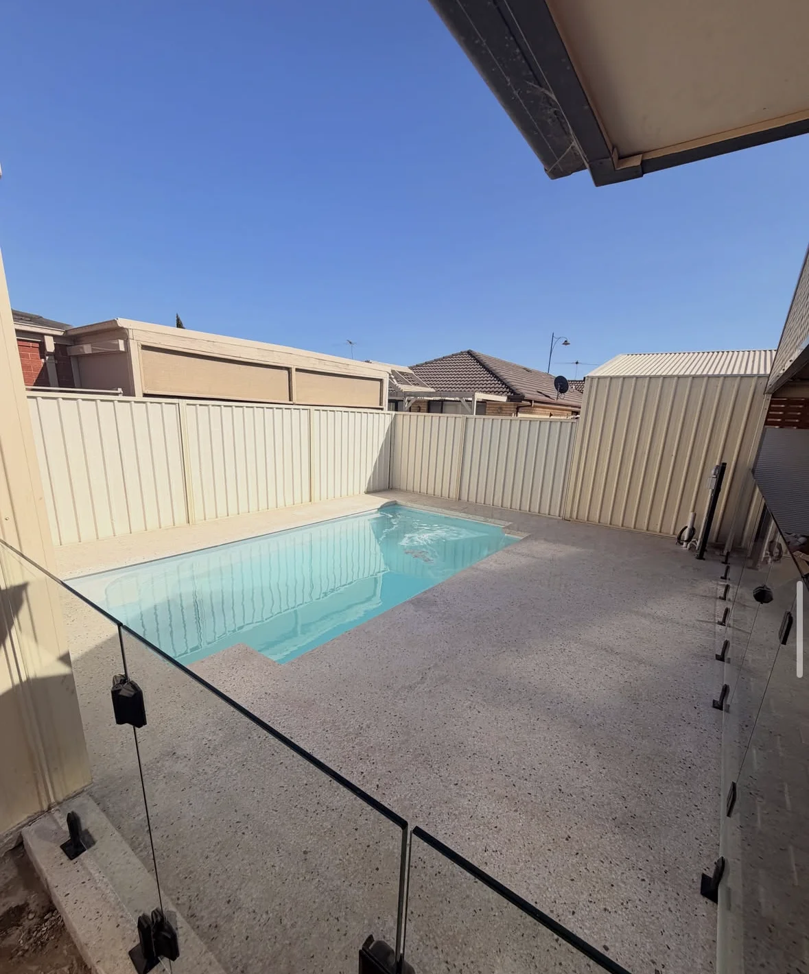 Finished concrete pool surround with glass fencing at Burton
