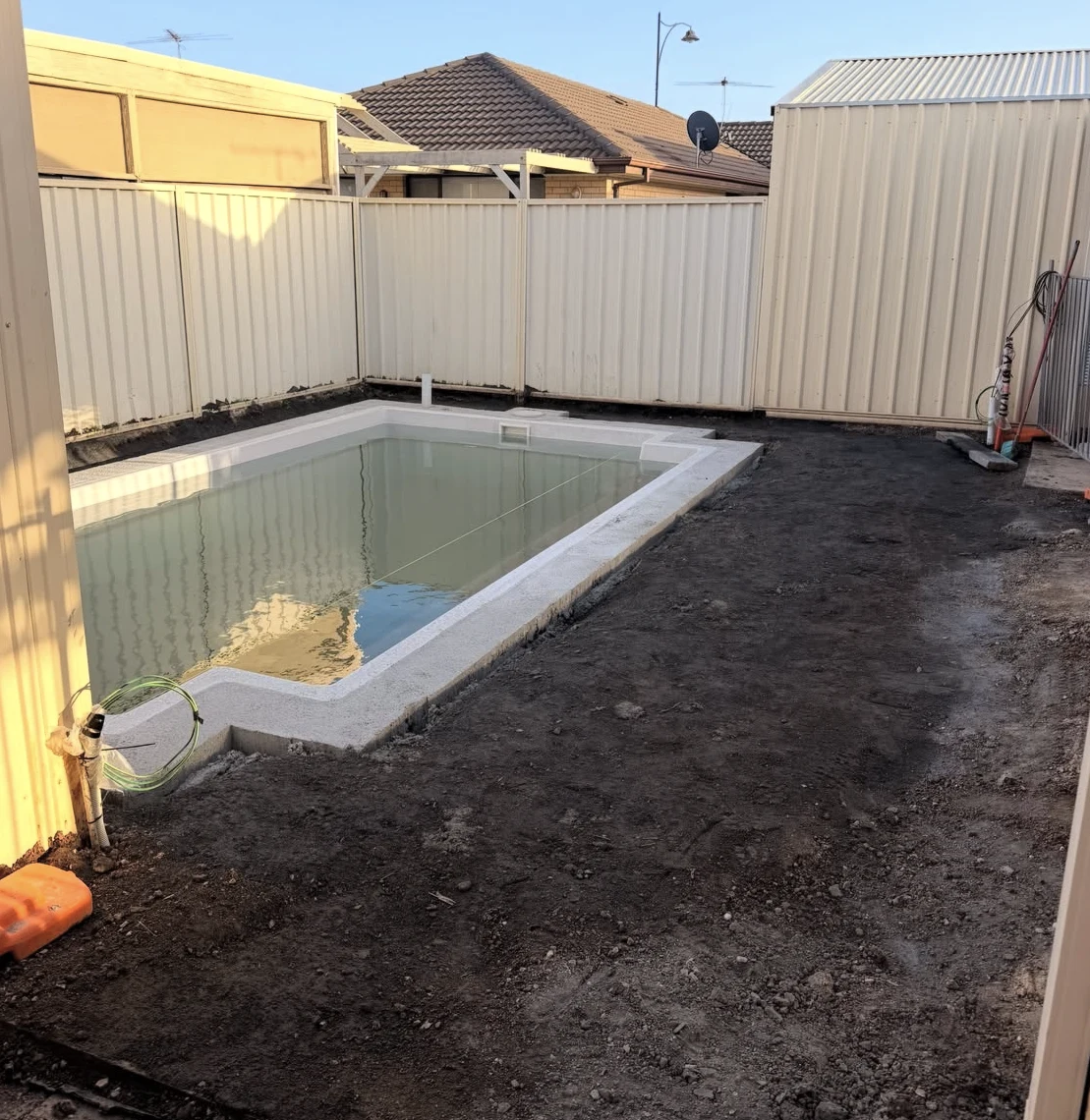 Before: bare ground around the installed Burton pool