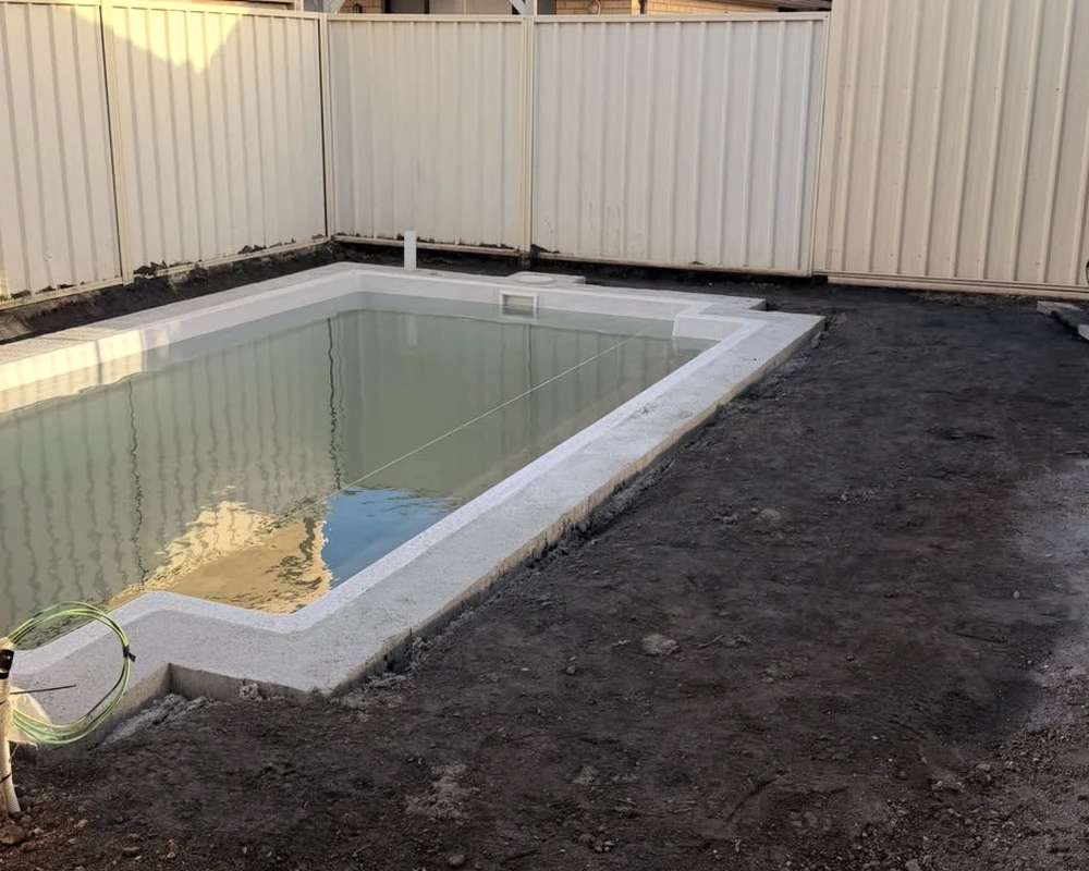 Before: bare ground around the installed Burton pool